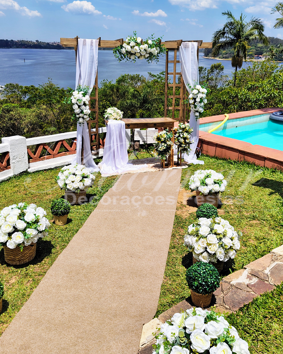Aluguel de decoração para cerimônia de casamento em Guarapiranga São Paulo com pergolado, cestos de palha, arranjos florais brancos e tapete para entrada dos noivos ao ar livre